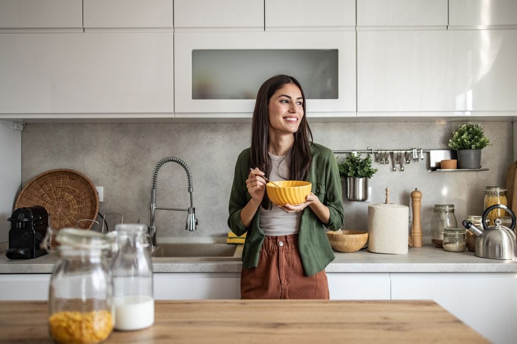 mujer joven comiendo de un bol en la cocina