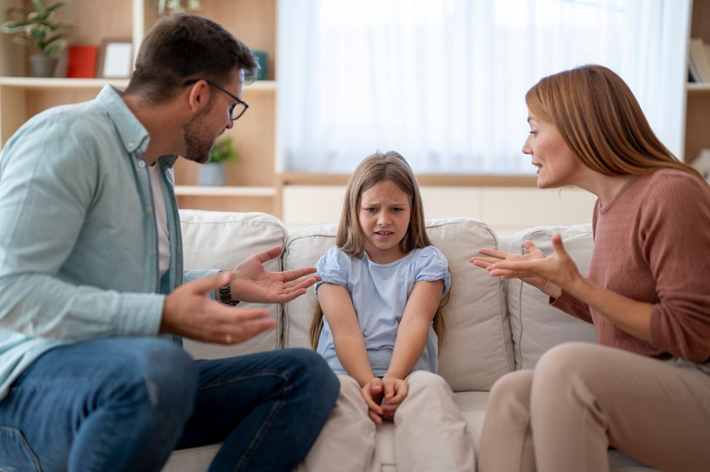 padres regañando a su hija, que está sentada en el sofá
