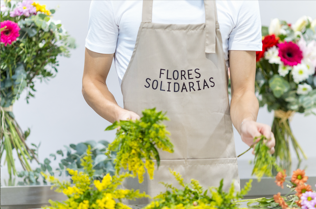 Primer plano de un trabajador con delantal de la marca Flores Solidarias trabajando con flores.