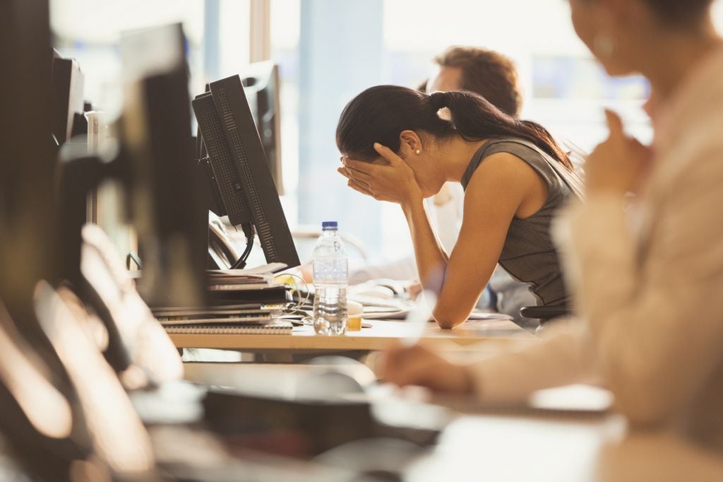 mujer agobiada en su puesto de trabajo, frente al ordenador