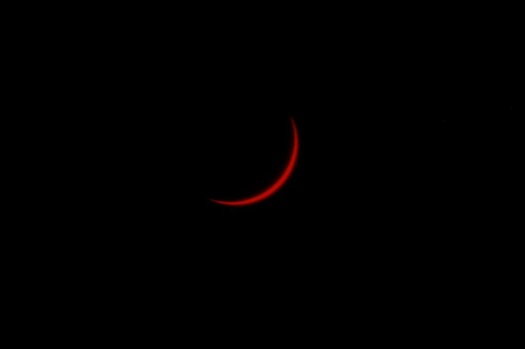 Un finísimo creciente rojizo es prácticamente todo lo que queda visible del Sol mientras la Luna avanza sobre él. La fotografía, tomada desde el Parque Forestal de Valdebebas-Felipe VI, en Madrid