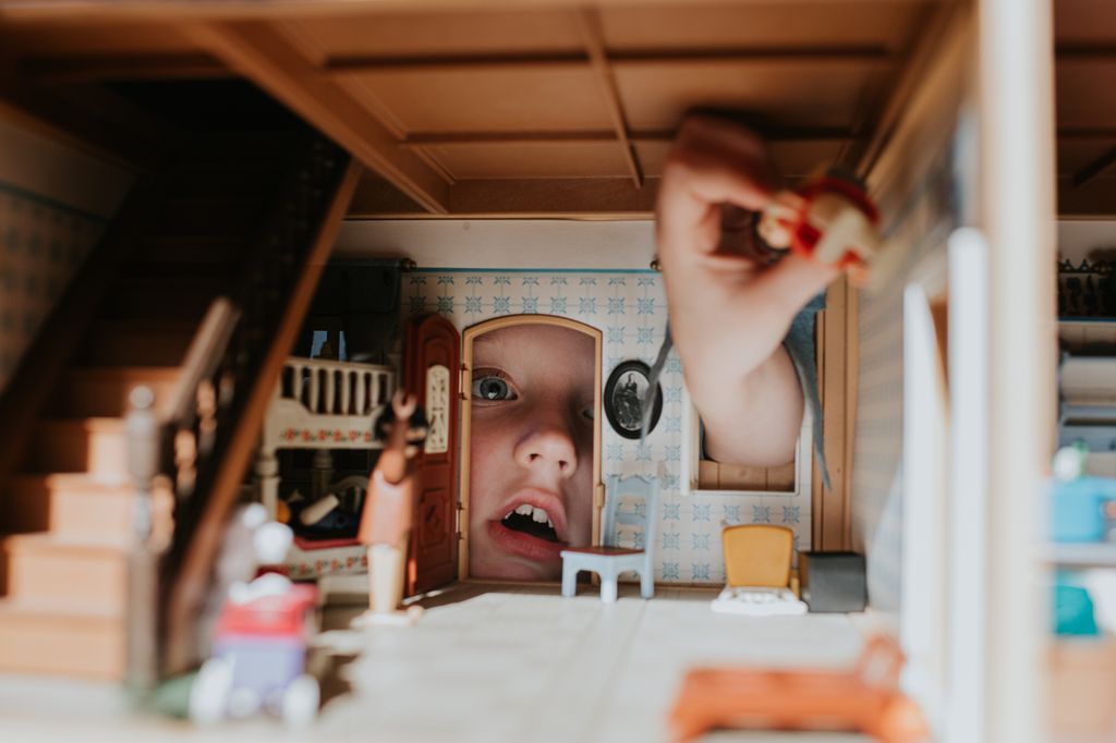 Niño jugando con playmobil en una casa de juguete