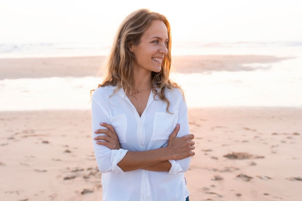 mujer sonriente sobre la arena de la playa