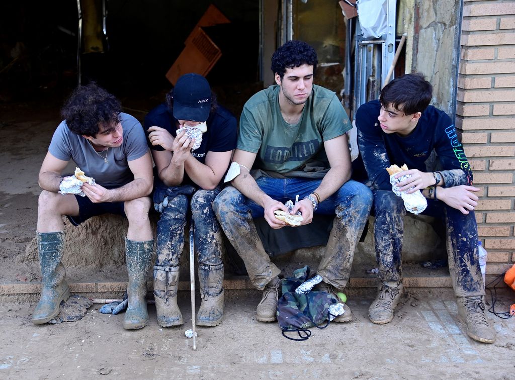 Plano medio de voluntarios de la DANA sentados mientras comen