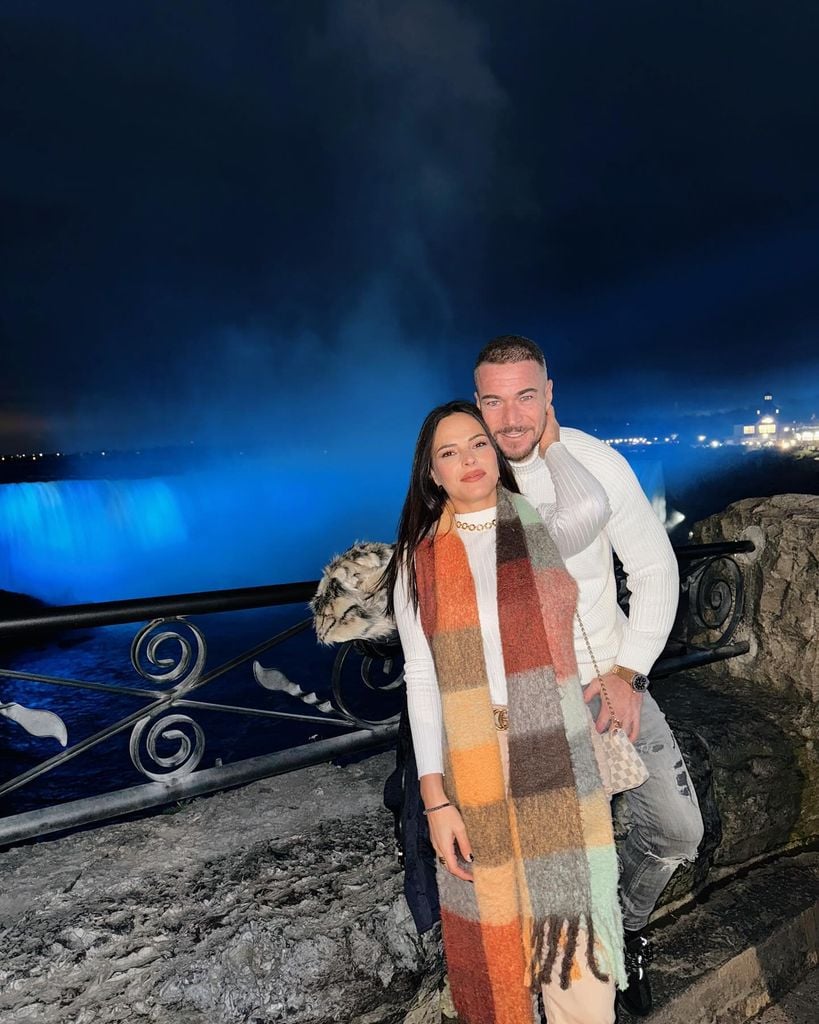Plano medio de Marta Peñate y Tony Spina posando con unas cataratas de fondo