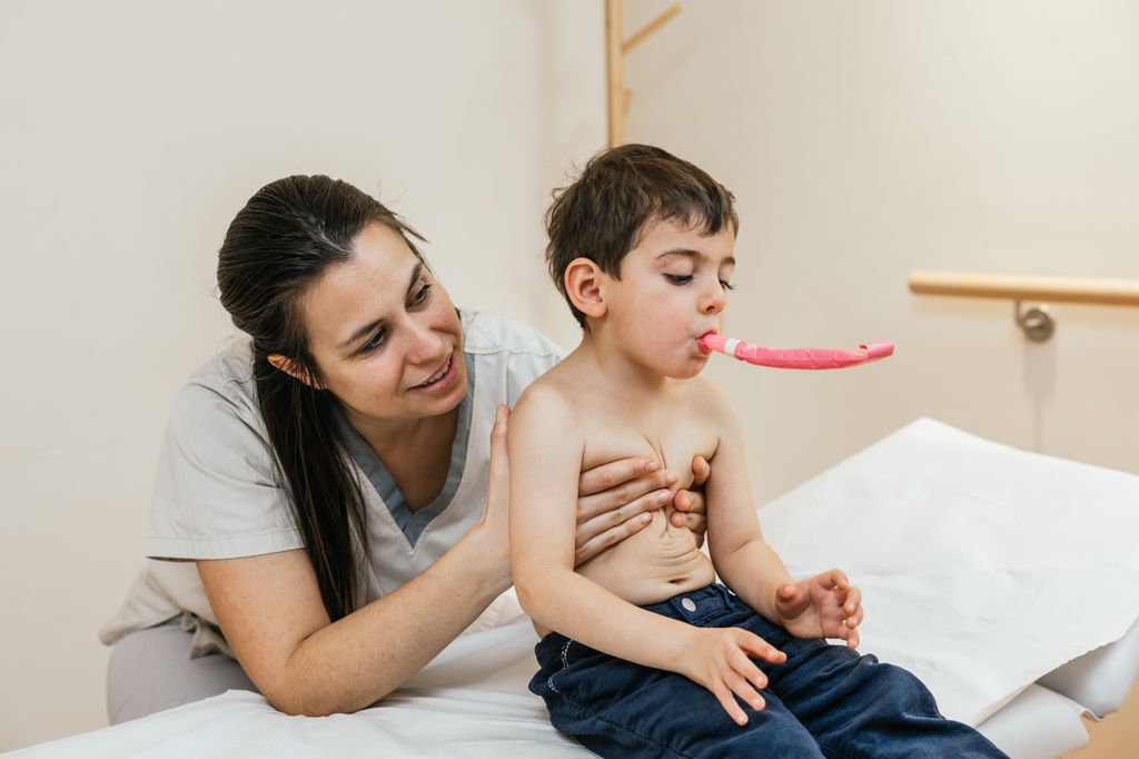 Fisioterapeuta respiratoria haciendo ejercicios con un niño