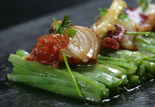 Plato de ejotes verdes con cebolla caramelizada y tocino encima, guarnición elegante.