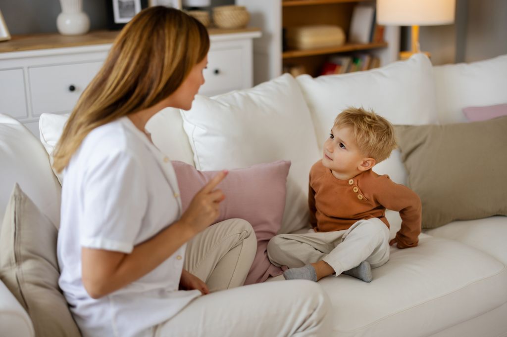Madre hablando con su hijo pequeño en el sofá