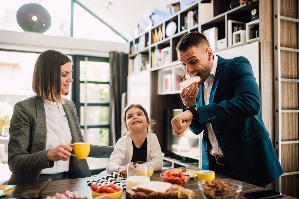 padres desayunando con su hija mientras miran al reloj