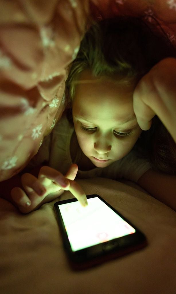 Niña con pantallas de noche