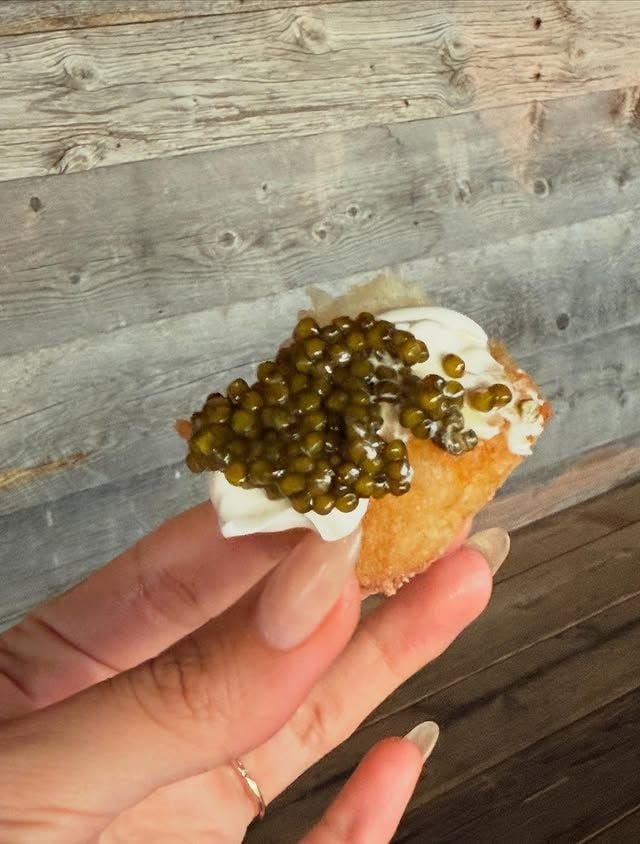 Mano de Hailey Bieber con canapé de caviar