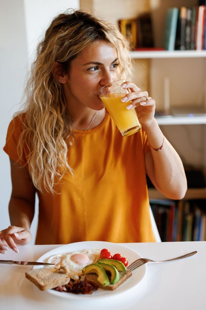 Una mujer desayunando huevos a la plancha con aguacate