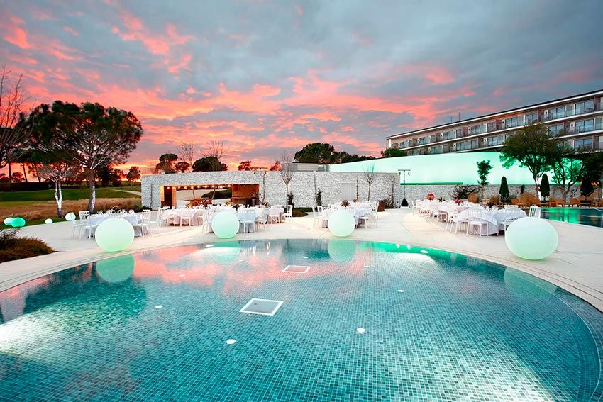 Terraza con mesas y sillas junto a la piscina del hotel Camiral Golf & Wellness