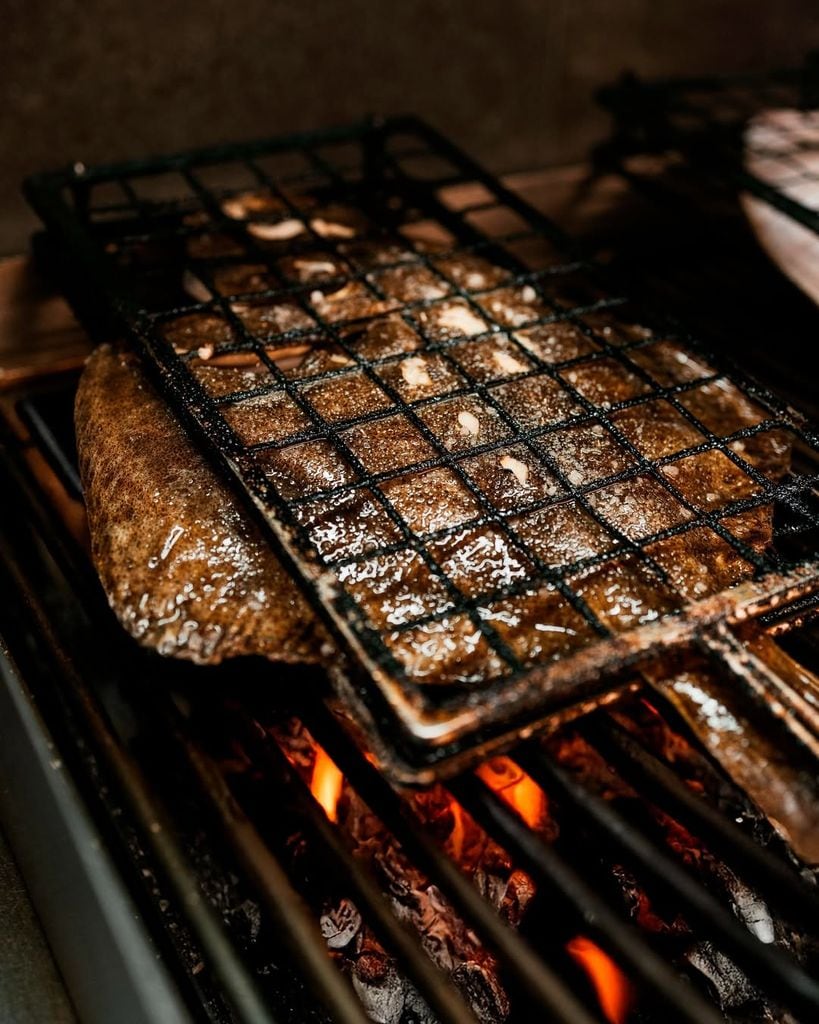 Espectaculares piezas de pescado, como este rodaballo, salen de las brasas de ambos restaurantes.