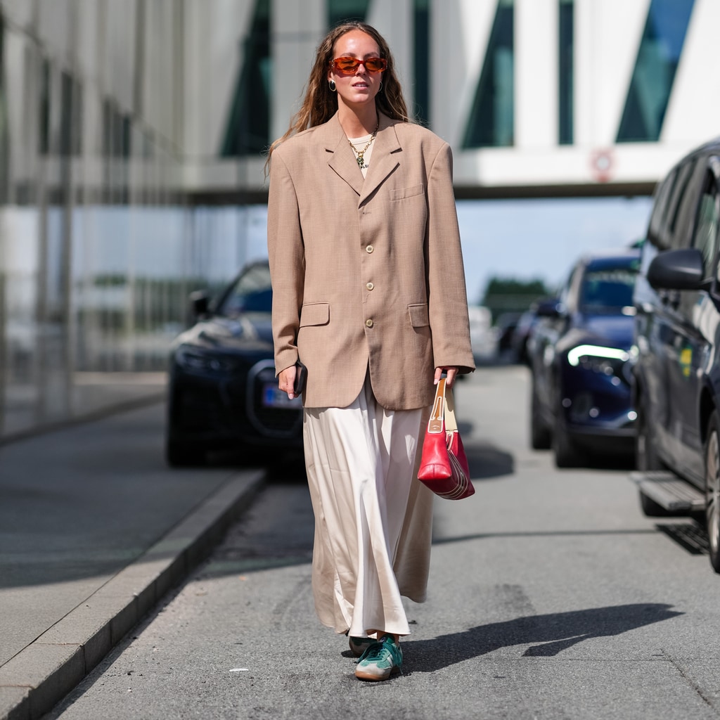Look con falda satinada blanca, americana y zapatillas verdes deportivas