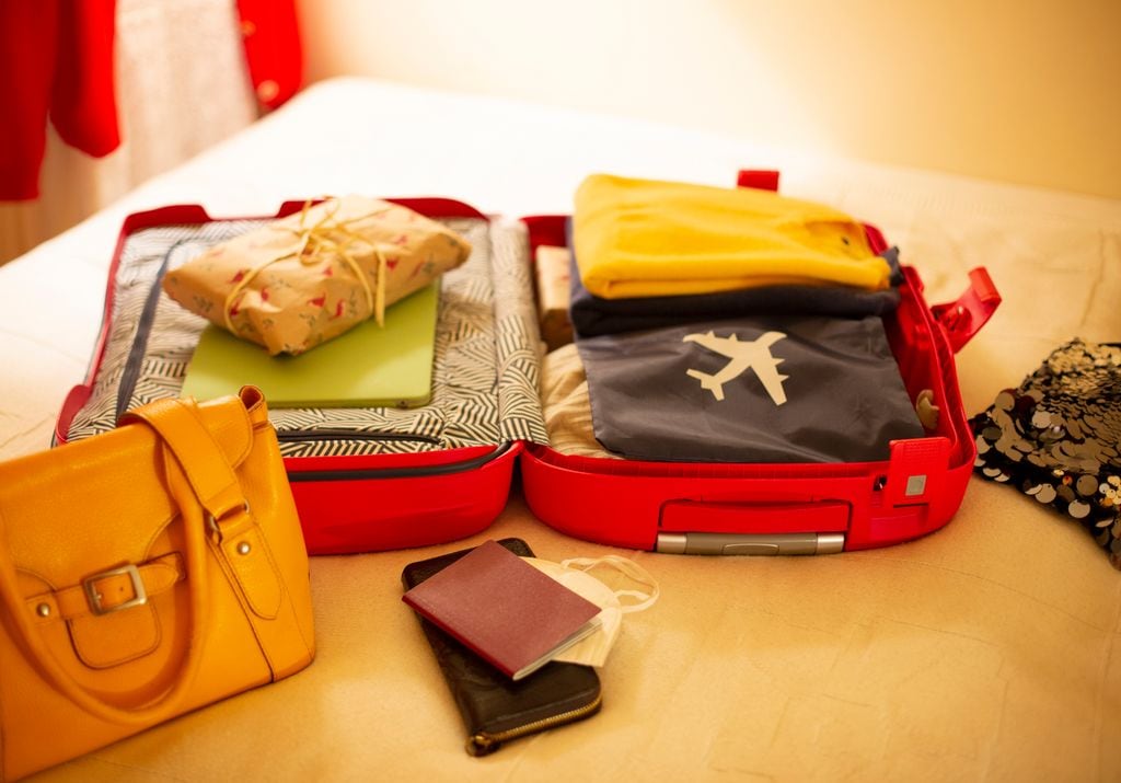 Maleta de cabina abierta sobre una cama con todo el equipaje preparada para volar