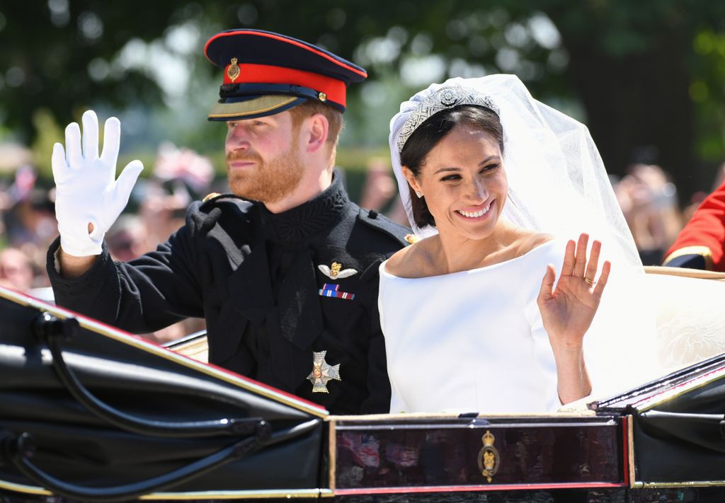 Plano medio de Harry y Meghan de Inglaterra saludando desde su carruaje tras la boda
