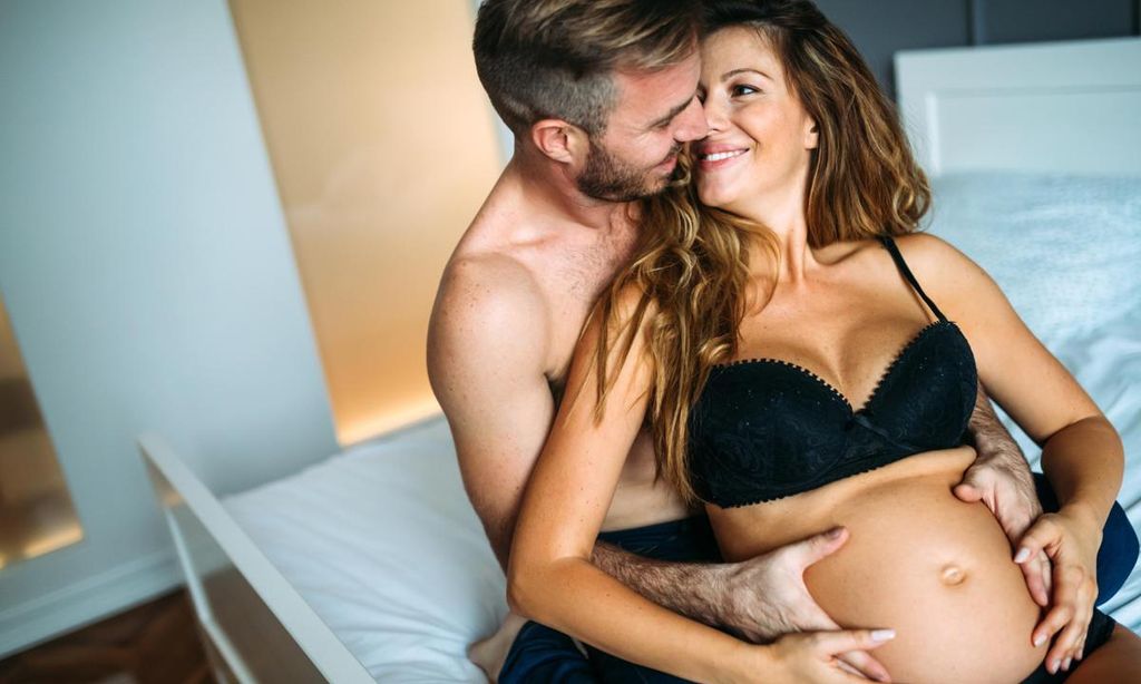 pareja amorosa en la cama con mujer embarazada