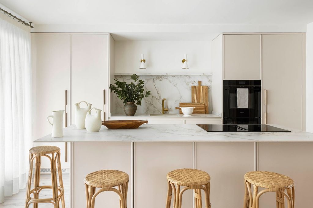 Cocina con muebles beige y encimera y antepecho con acabado en mármol.