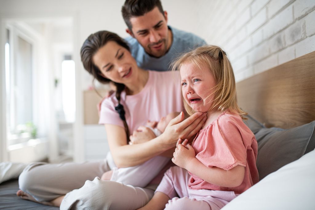 Niña pequeña llorando consolada por sus padres