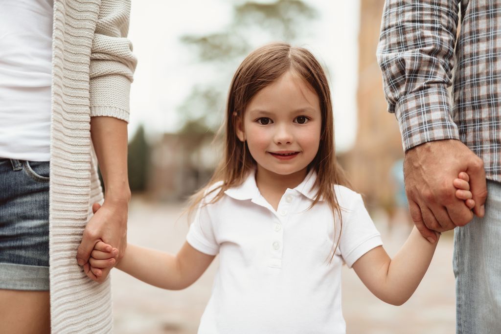 Niña feliz de la mano de sus padres