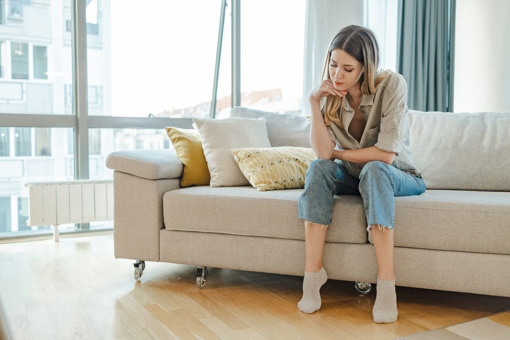 mujer joven aburrida y sin energía sentada en el sofá