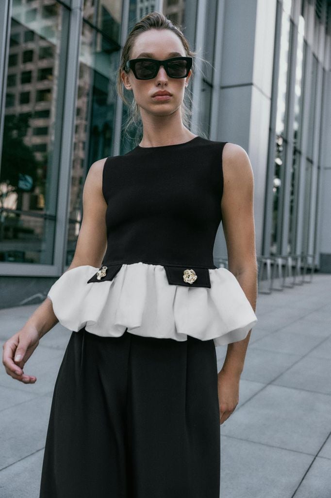 Top confeccionado en tejido elástico. Cuello barco y manga sisa