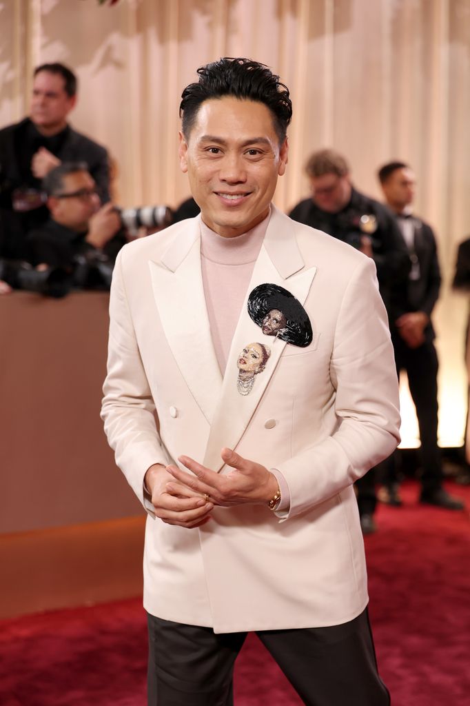 El director Jon M. Chu lleva dos broches, uno de Ariana Grande y otro de Cynthia Erivo, en los Globos de Oro 2026