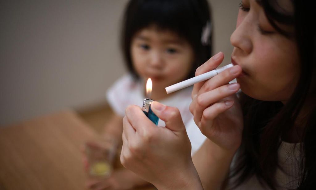 madre fumando delante de su hija