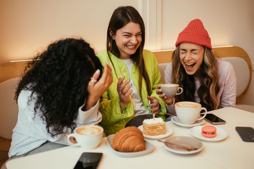 Tres amigas en un desayuno hablando y riendo