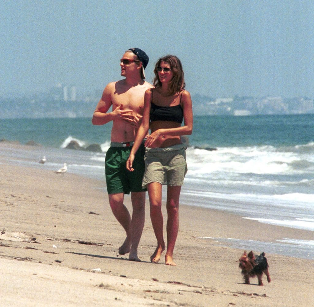 Plano entero de Leonardo DiCaprio paseando en una playa con Gisele Bundchen