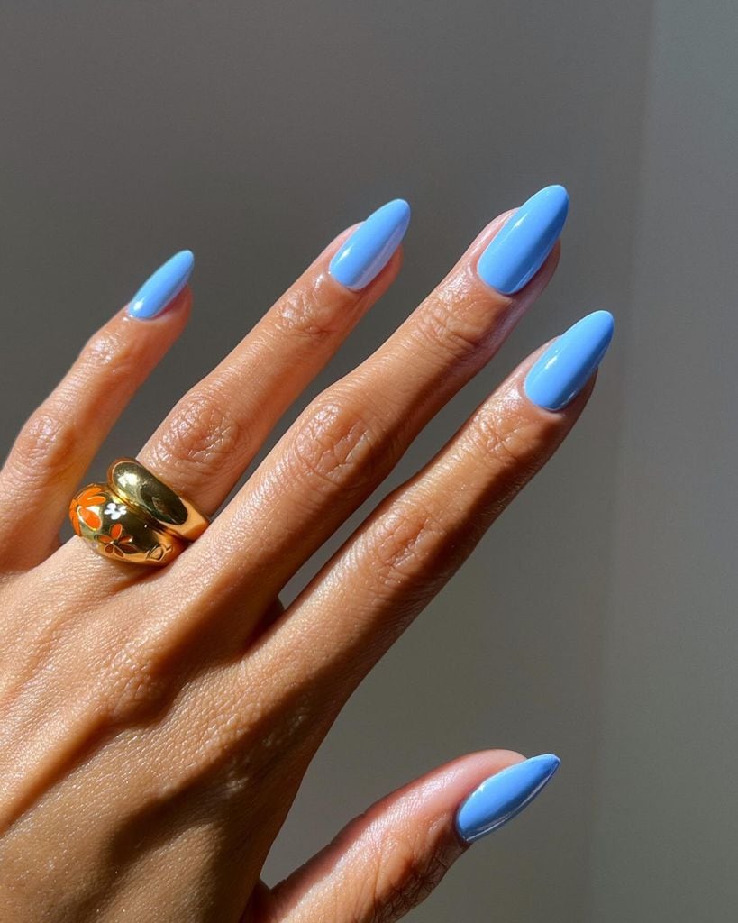 Manos con manicura azul y anillo dorado
