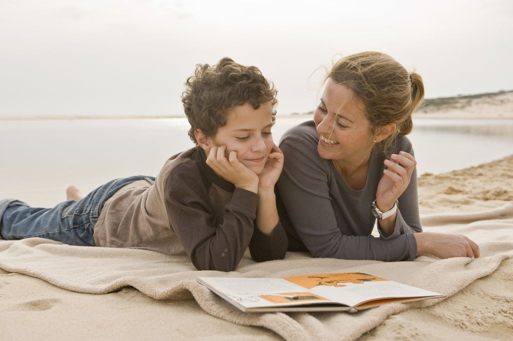 Madre leyendo con su hijo en la playa