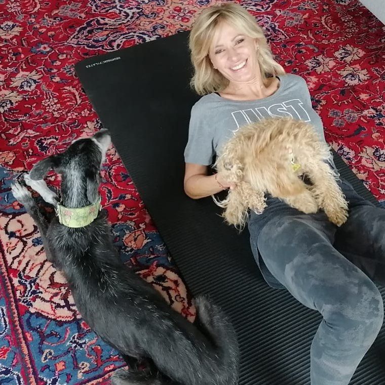 Susanna Griso tumbada con sus perros en una alfombra de casa