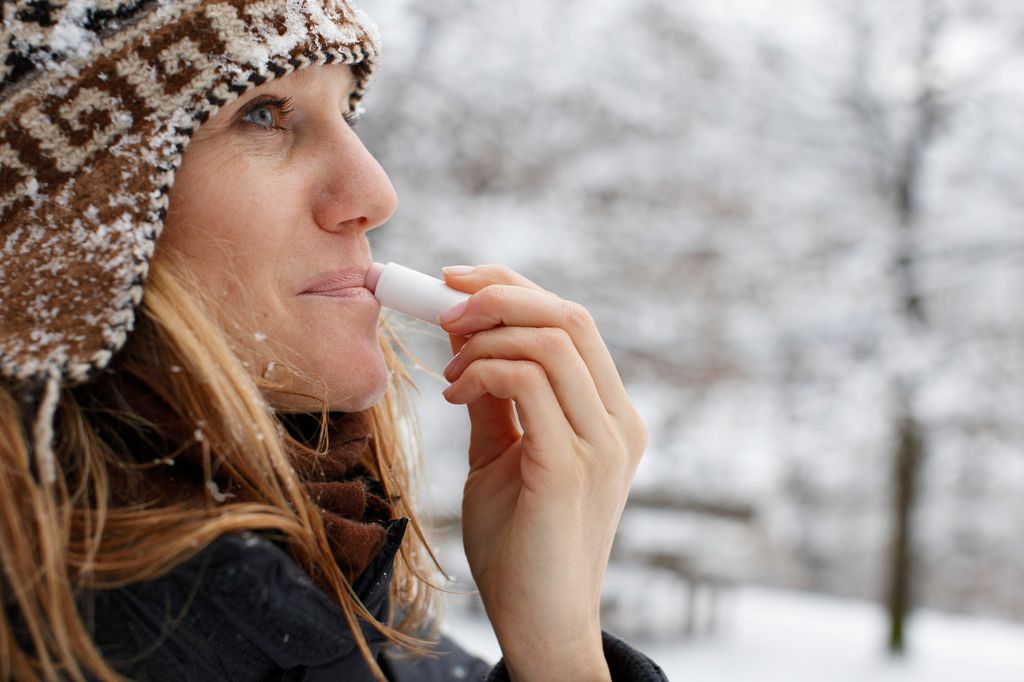 mujer en un día de invierno usando un bálsamo labial