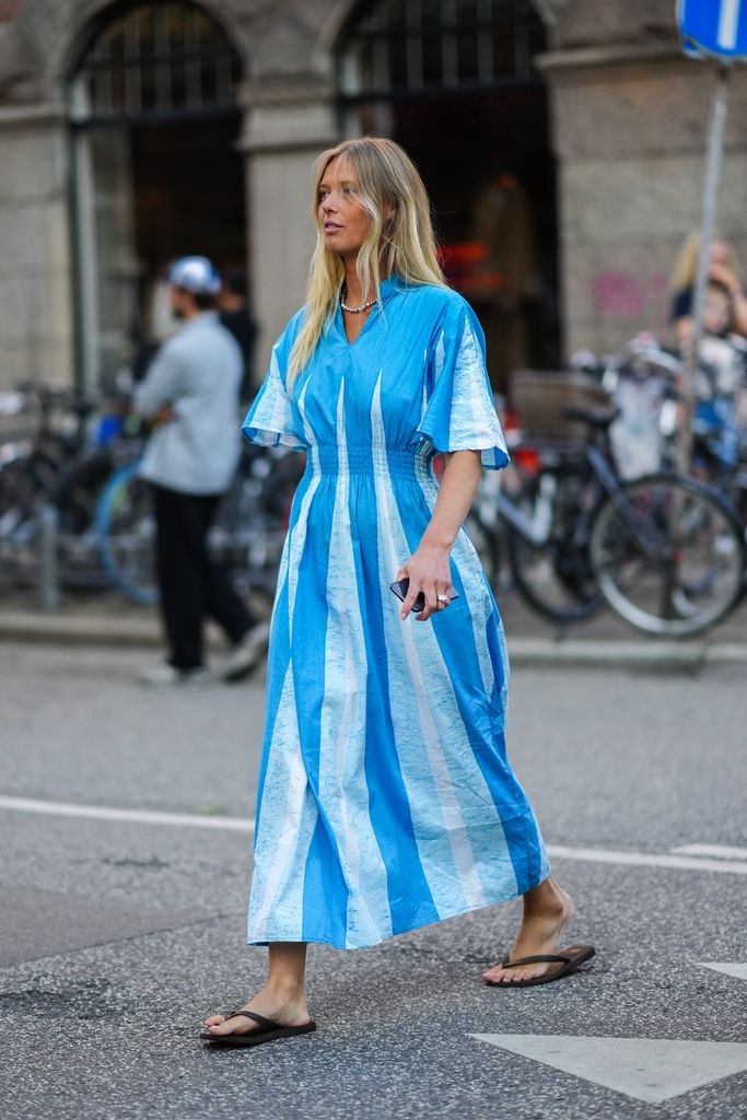 COPENHAGUE, DINAMARCA - 10 DE AGOSTO: Una invitada lleva un collar de perlas de plata, un patrón de impresión azul y azul pálido / mangas cortas acampanadas / vestido largo, anillos de plata, chanclas negras, fuera de Baum und Pferdgarten, durante la Semana de la Moda de Copenhague Primavera/Verano 2023, el 10 de agosto de 2022 en Copenhague, Dinamarca. (Foto de Edward Berthelot/Getty Images)