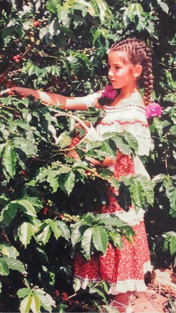 Maria Palacio, de niña, en la finca de su familia recolectando el grano de café.