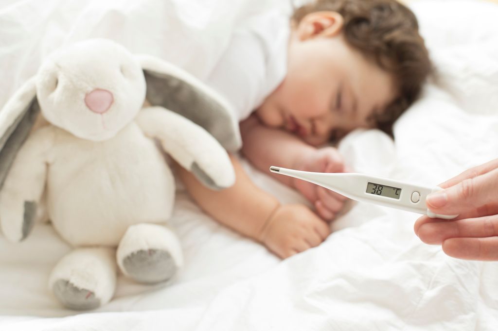 niño con fiebre dormido en la cama