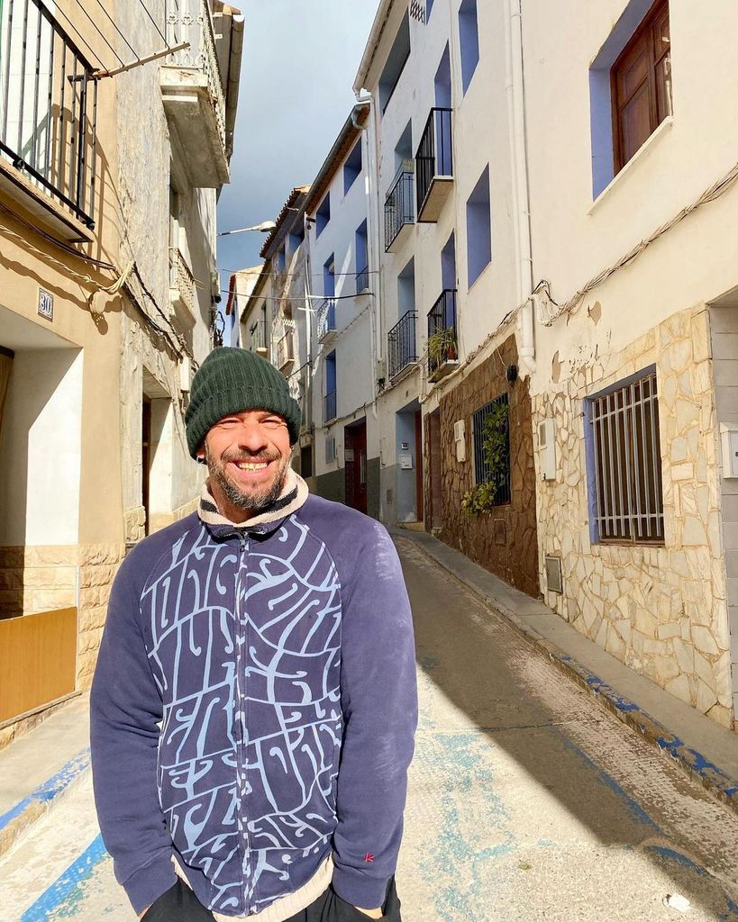 Plano medio de Nacho Palau en un pueblo con gorro verde y sudadera azul