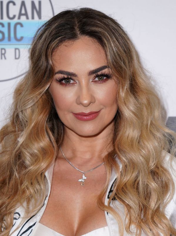 Aracely Arámbula con cabello suelto con ondas y jacket blanca 