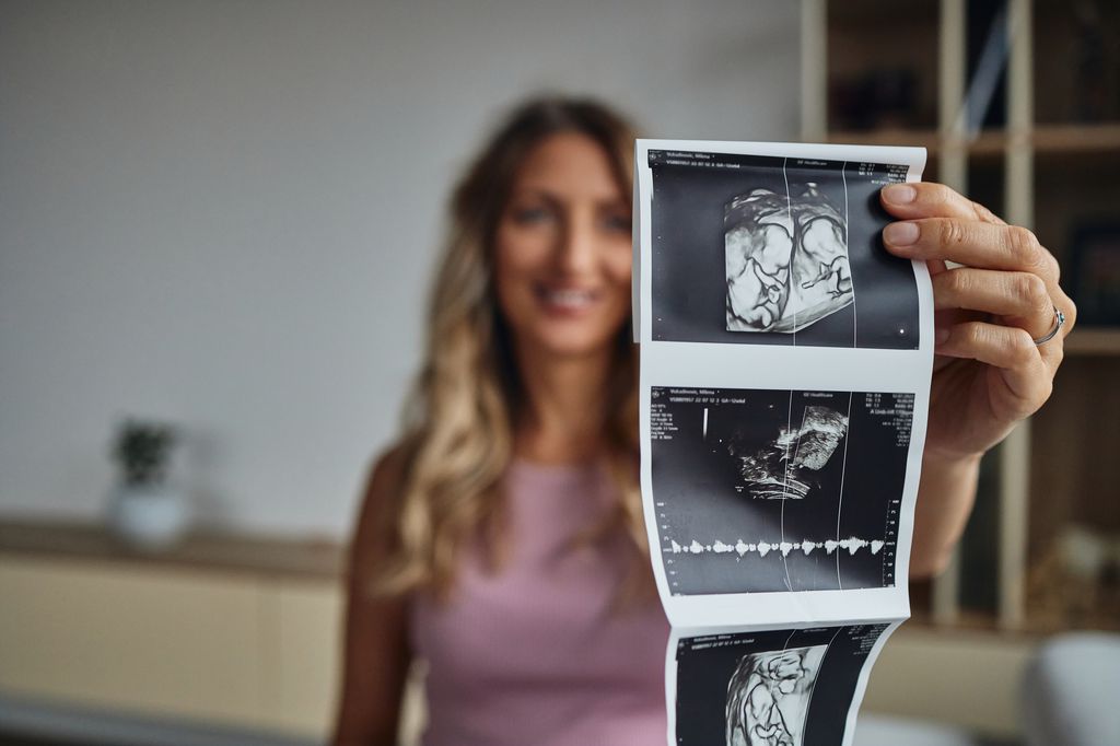 Embarazada de gemelos con la ecografía de sus dos bebés