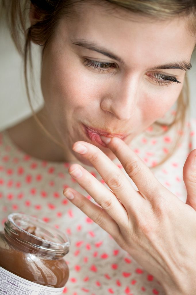 Mujer comiendo con los dedos un bote de crema de cacao