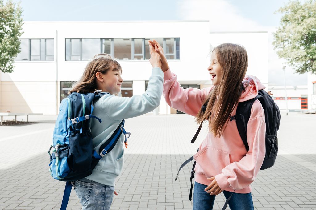 adolescentes chocando las manos delante del colegio