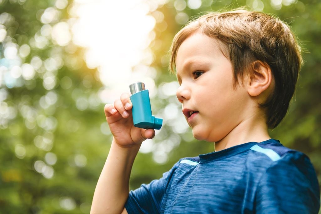 Niño con asma usando inhalador