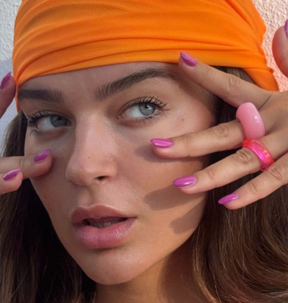 Laura Escanes con bandana naranja, manicura rosa y anillos de resina