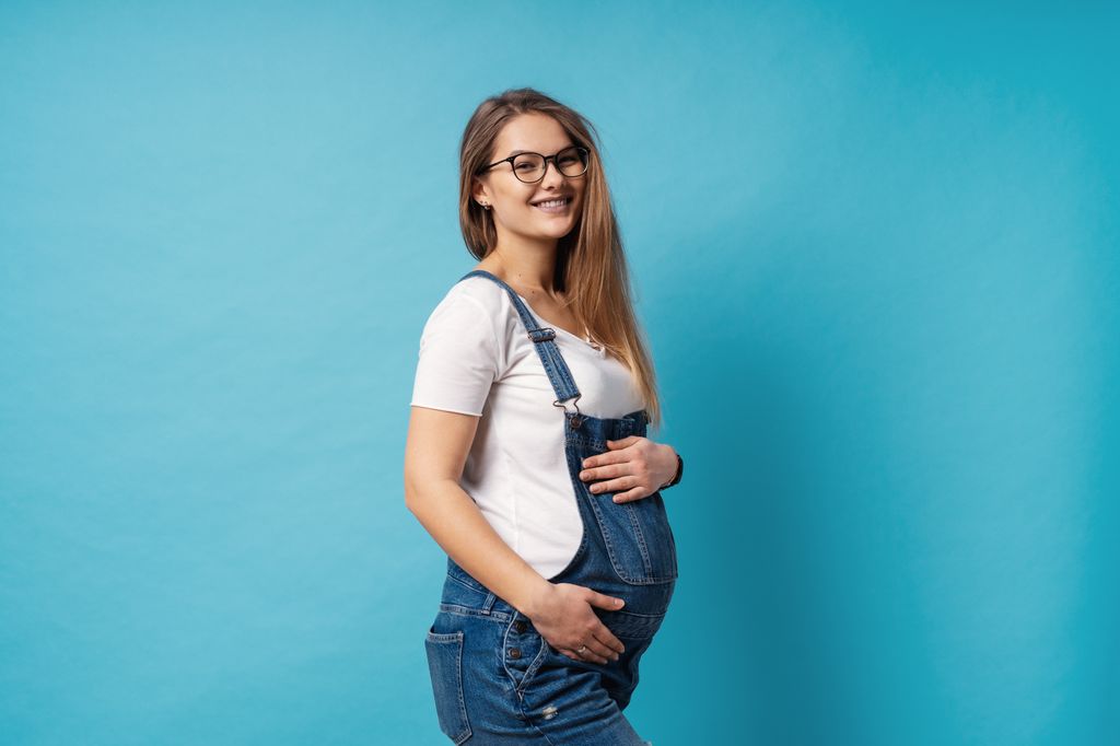 Mujer embarazada con gafas y sonriente