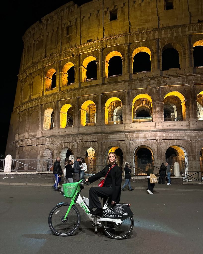 Plano entero de Chiara Ferragni montando en bici en los alrededores del Coliseo de Roma