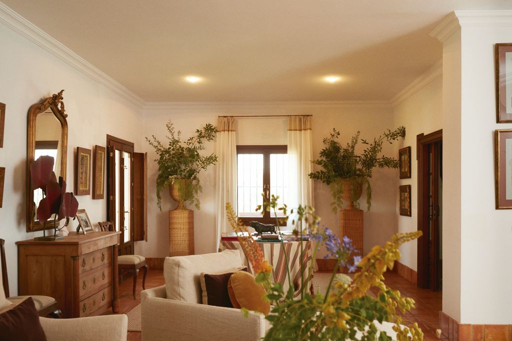 La finca de Roca Rey en Sevilla, por dentro: uno de los salones con muebles tradicionales, de madera noble y muchos adornos florales