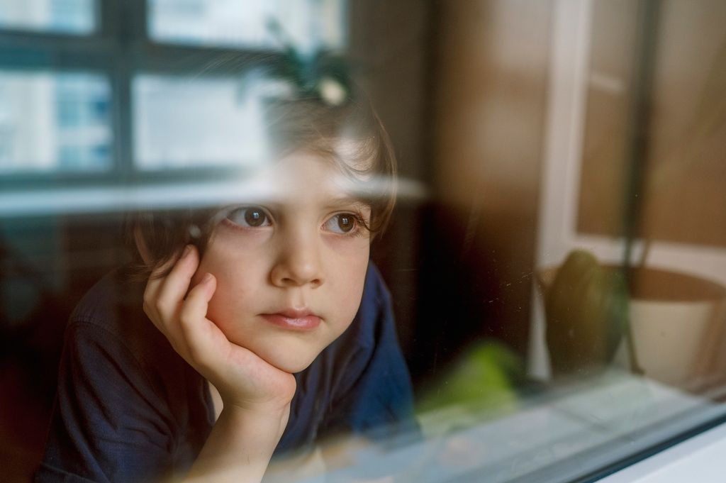 Niño mirando por la ventana muy concentrado