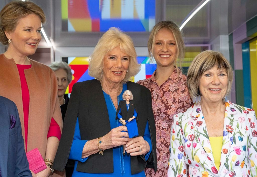 Plano medio de la Reina Camilla y Matilde de Bélgica en un evento con una muñeca barbie